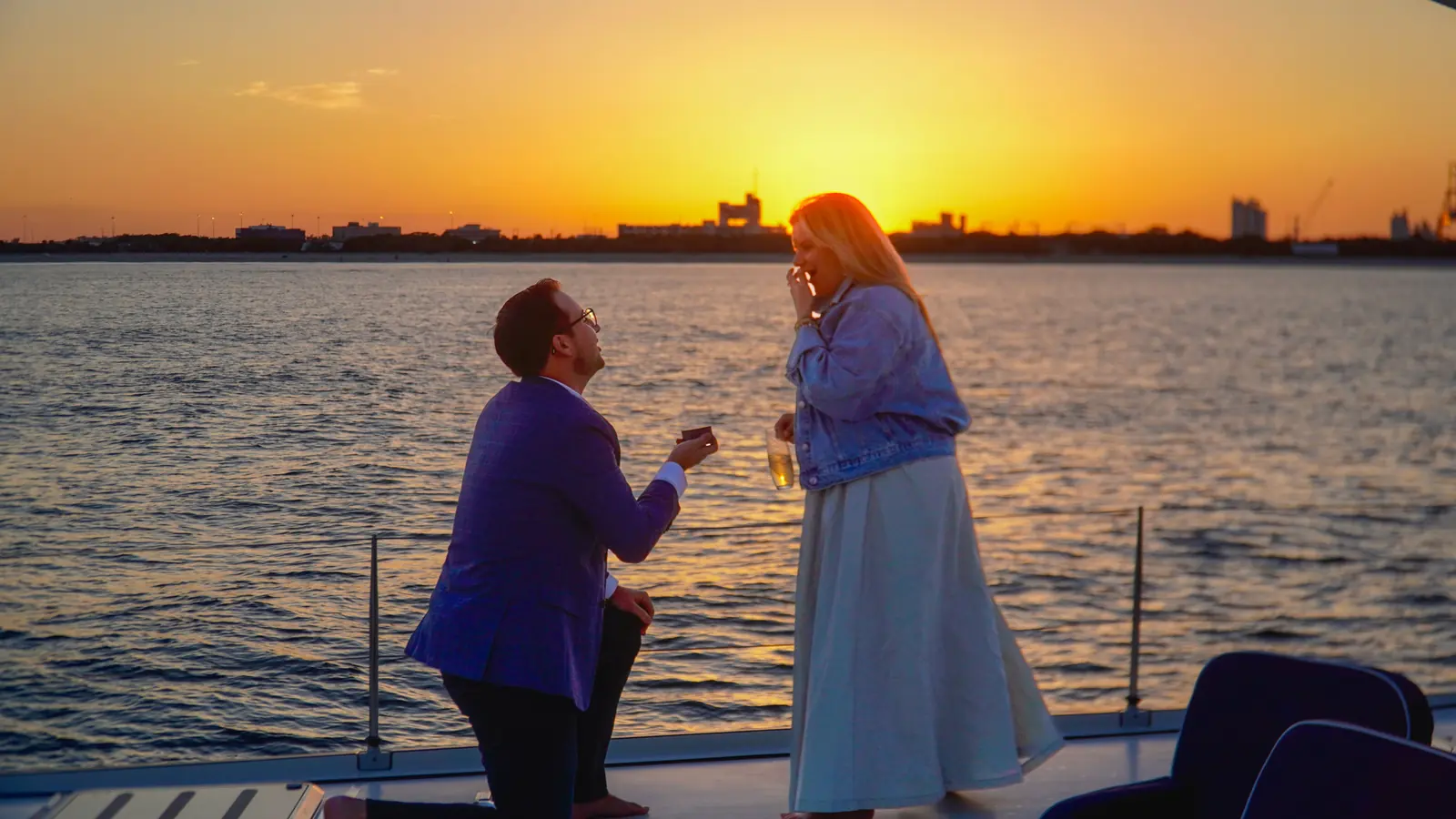 Couple celebrating a yacht proposal at sunset