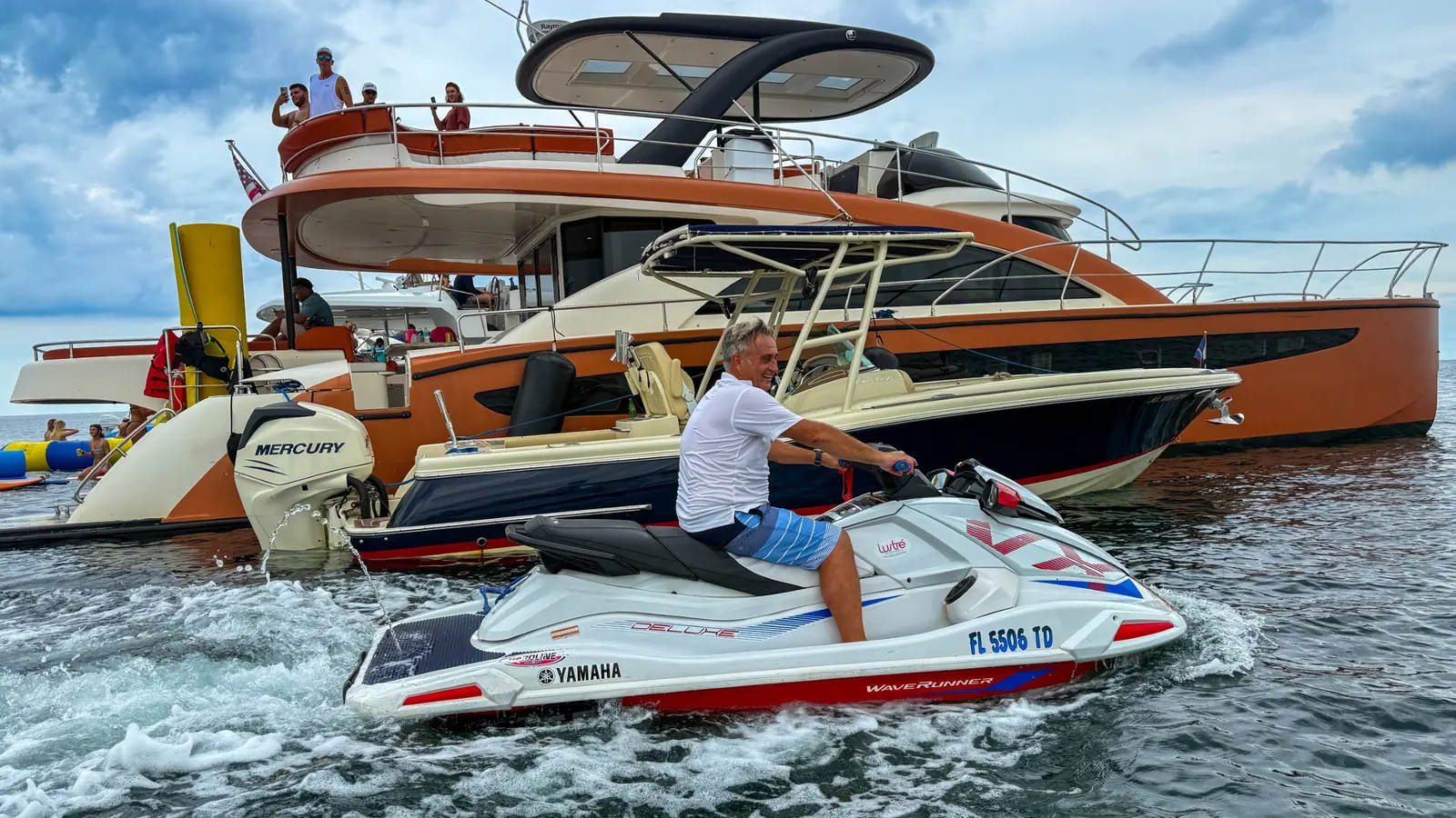 Jet ski riding across the water near a private yacht